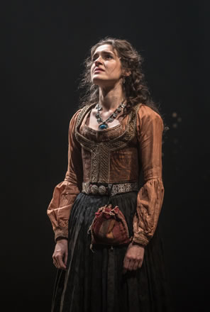 Jessica in highly decorated peasant type dress, a brown blouse and green pleated dress with fabric purse dangling from her metalic belt